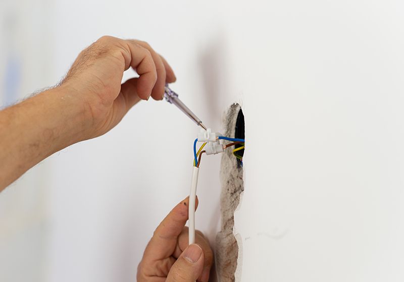 Primer plano de un electricista trabajando en cables de una regleta. Trabajo de electricidad.