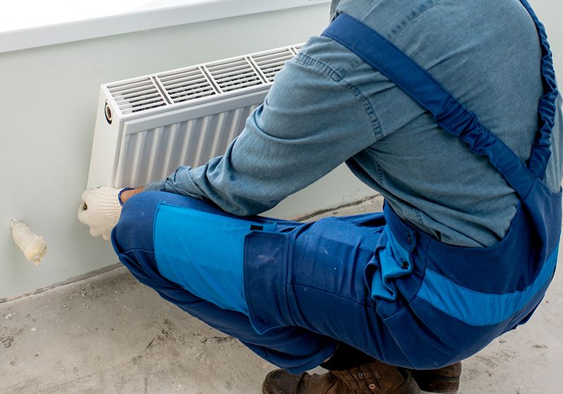 Un técnico de fontanería colocando un radiador en una obra.